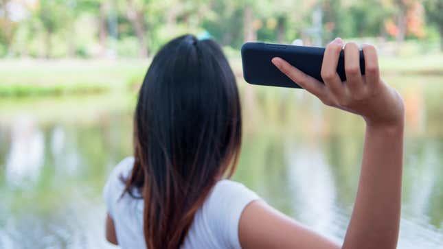 A woman raises her arm to throw her phone into a lake