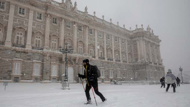 People walk on the snow next to the Royal Palace during heavy snowfall on January 09, 2021 in Madrid, Spain.