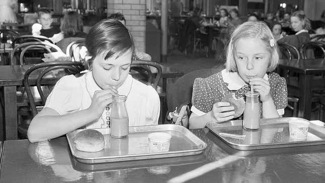 Black and white image of two young girls drinking chocolate milk out of straws