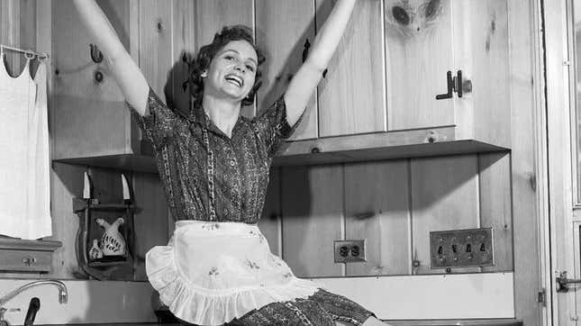 1950s housewife smiling sitting on countertop
