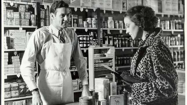 Vintage photograph of a woman reading her grocery list to the man at the counter