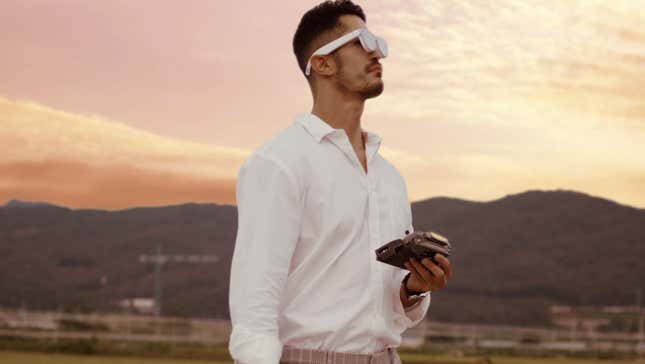Man wearing AR glasses stares thoughtfully into the sunset holding a remote control, likely wondering where his drone went.