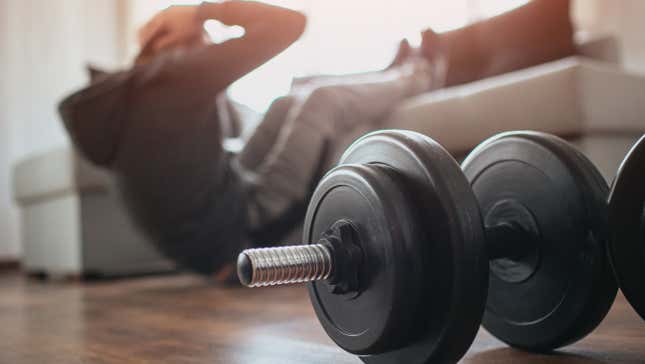 dumbbell in foreground, exerciser behind