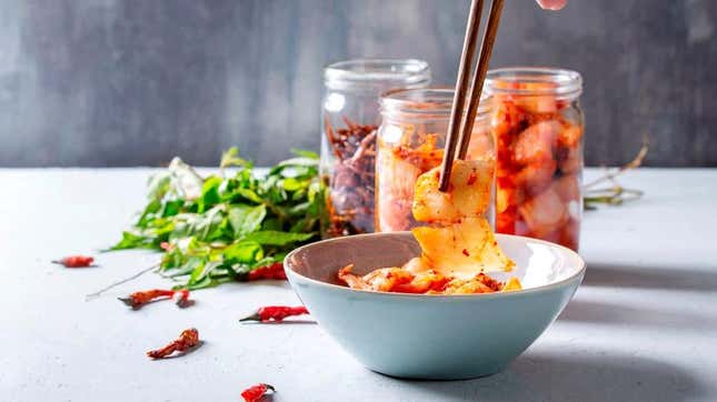 chopsticks dipping into a bowl of kimchi