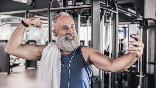 bearded man flexing for a selfie at the gym