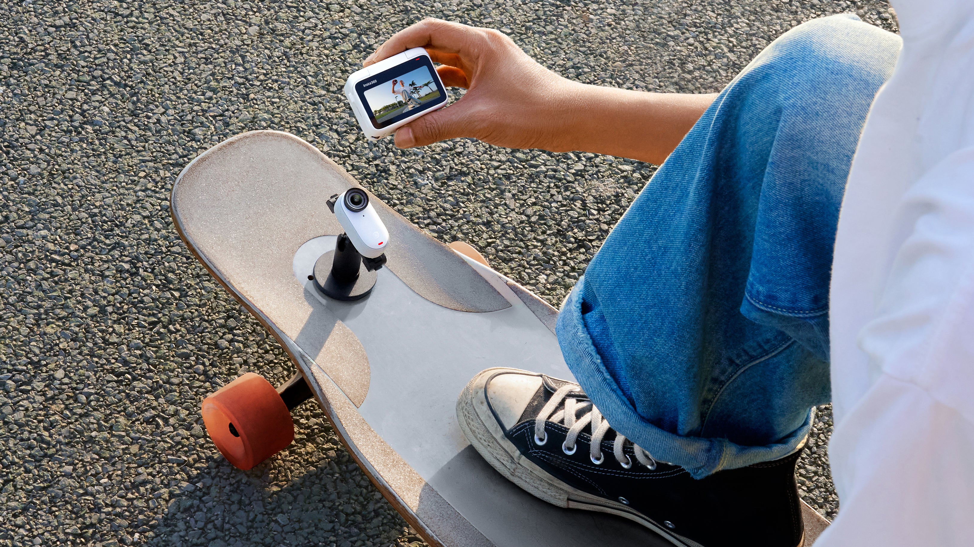 Une personne avec une caméra Insta360 GO 3 fixée à un support sur un snowboard utilisant un accessoire Pod pour afficher un aperçu en direct de ce qui est enregistré.