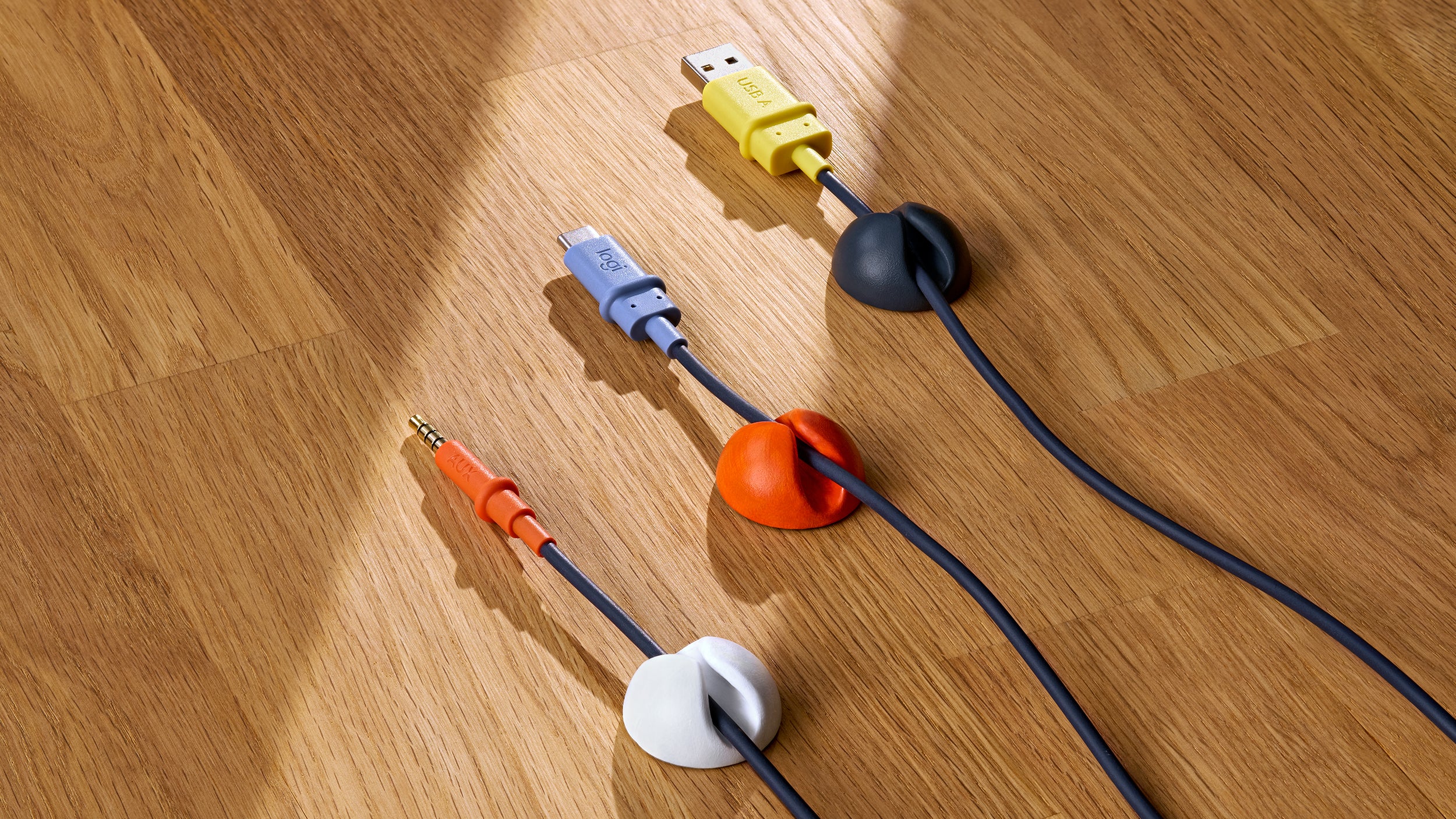 تتوفر خيارات توصيل الكابلات الثلاثة لسماعات Logitech Zone Learn على مكتب خشبي: صوت 3.5 ملم و USB-C و USB-A.