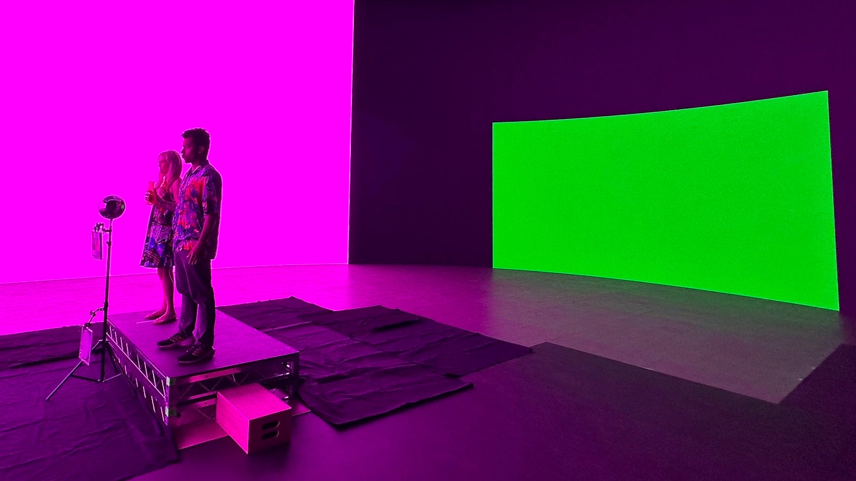 يقف الممثلون على مجموعة محاطة بشاشة LED كبيرة مضاءة بخلفية خضراء وإضاءة أمامية باللونين الأحمر والأزرق.