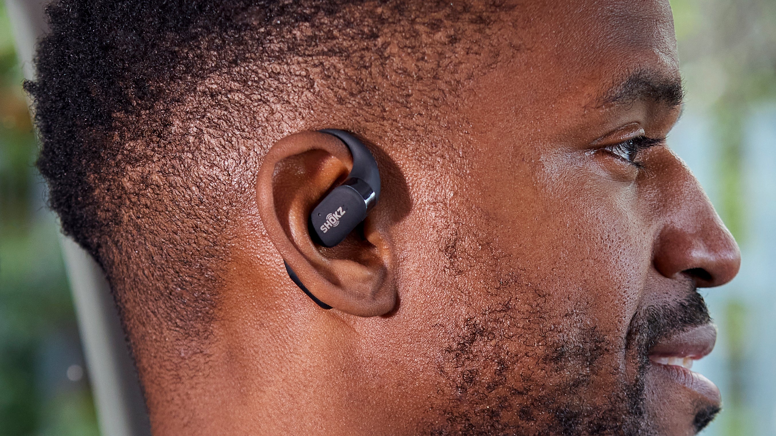 شخص يرتدي إصدار اللون الأسود من سماعات الأذن اللاسلكية Shokz OpenFit.
