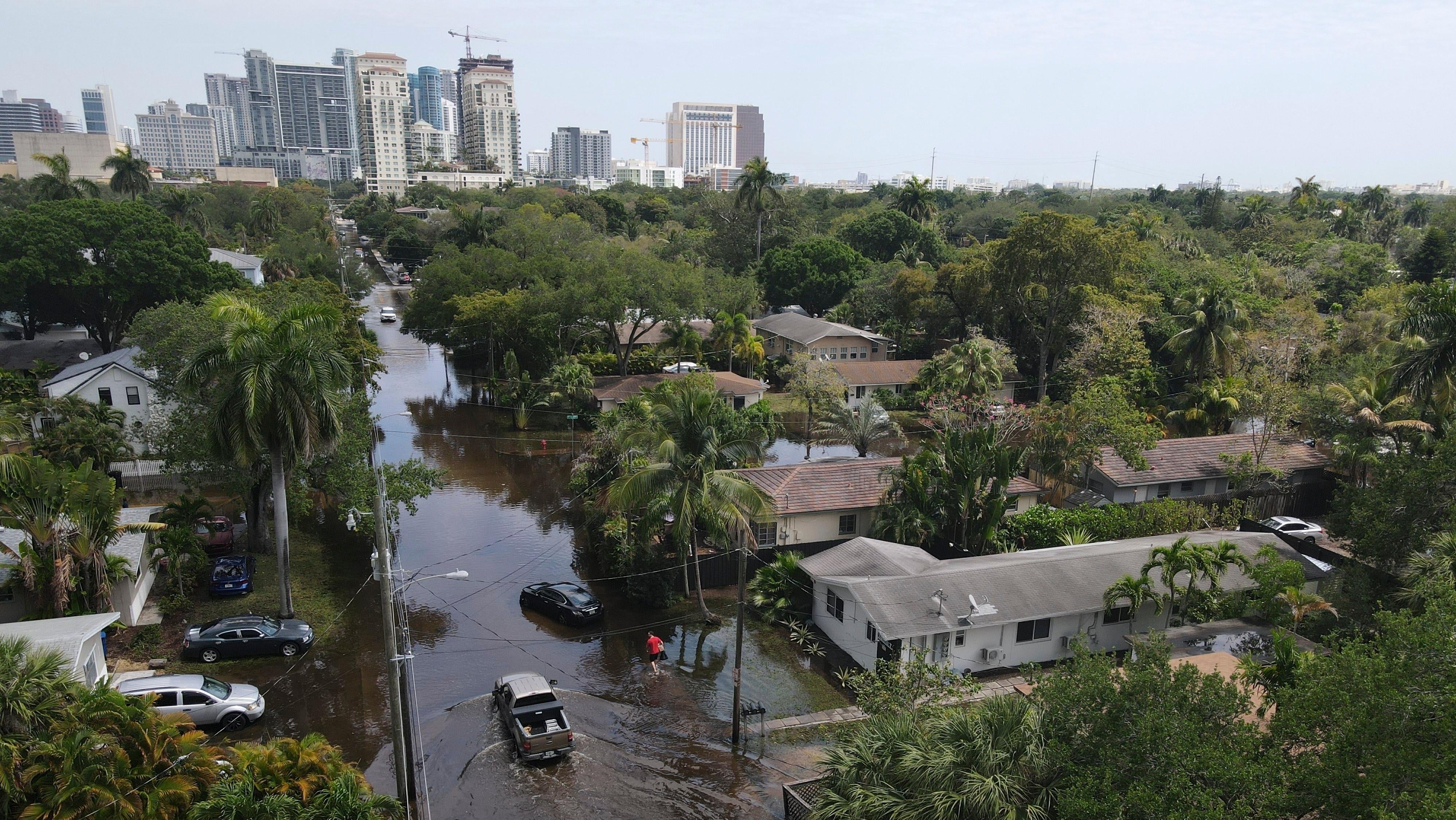 تشق الشاحنات والمقيم على الأقدام طريقهم عبر مياه الفيضانات المتراجعة في حي Sailboat Bend في Fort Lauderdale ، فلوريدا في 13 أبريل 2023.