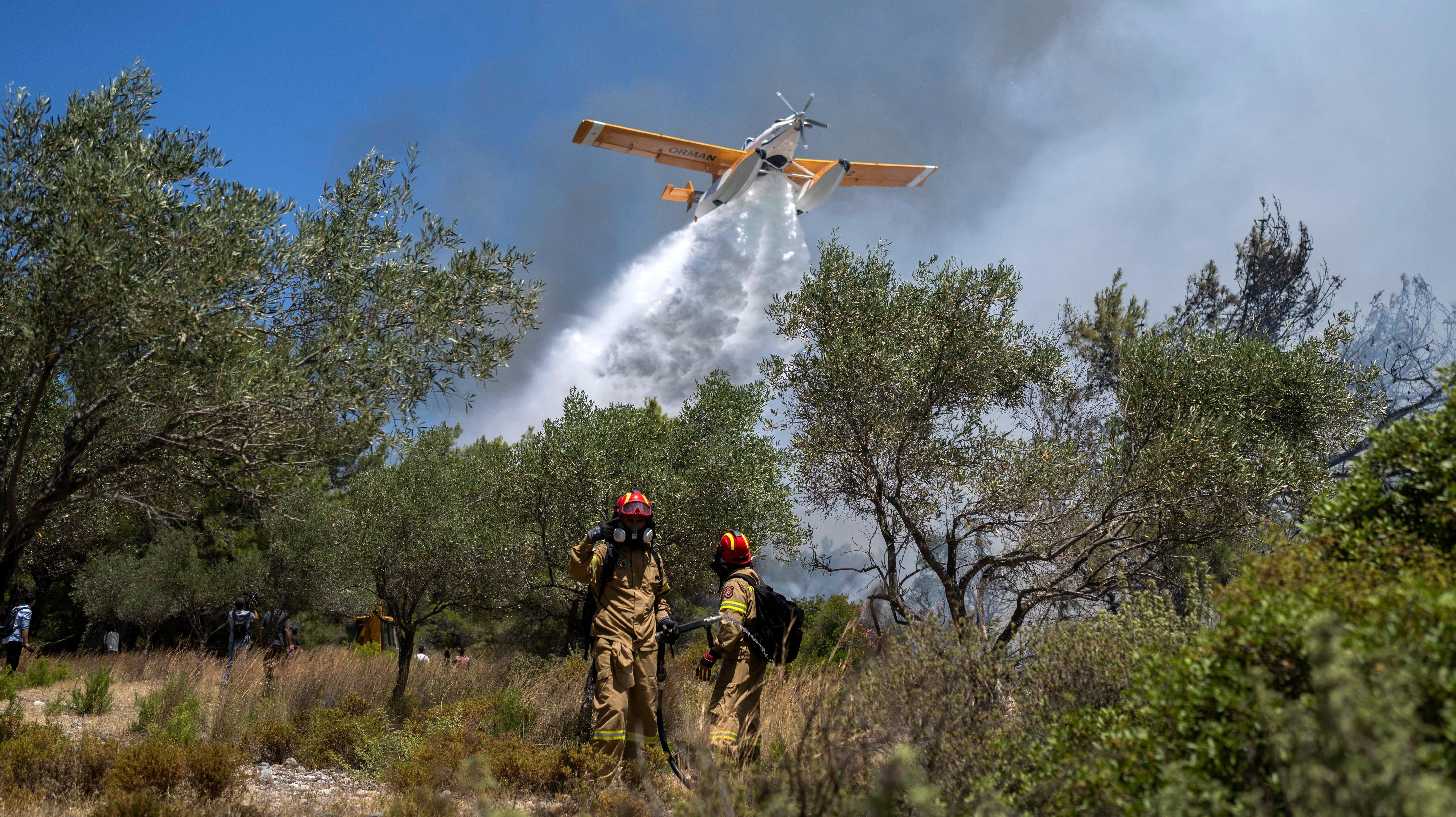 طائرة تسقط المياه بينما يعمل رجال الإطفاء أثناء حريق غابات في قرية فاتي ، في جزيرة رودس في بحر إيجه ، جنوب شرق اليونان ، في 25 يوليو 2023.