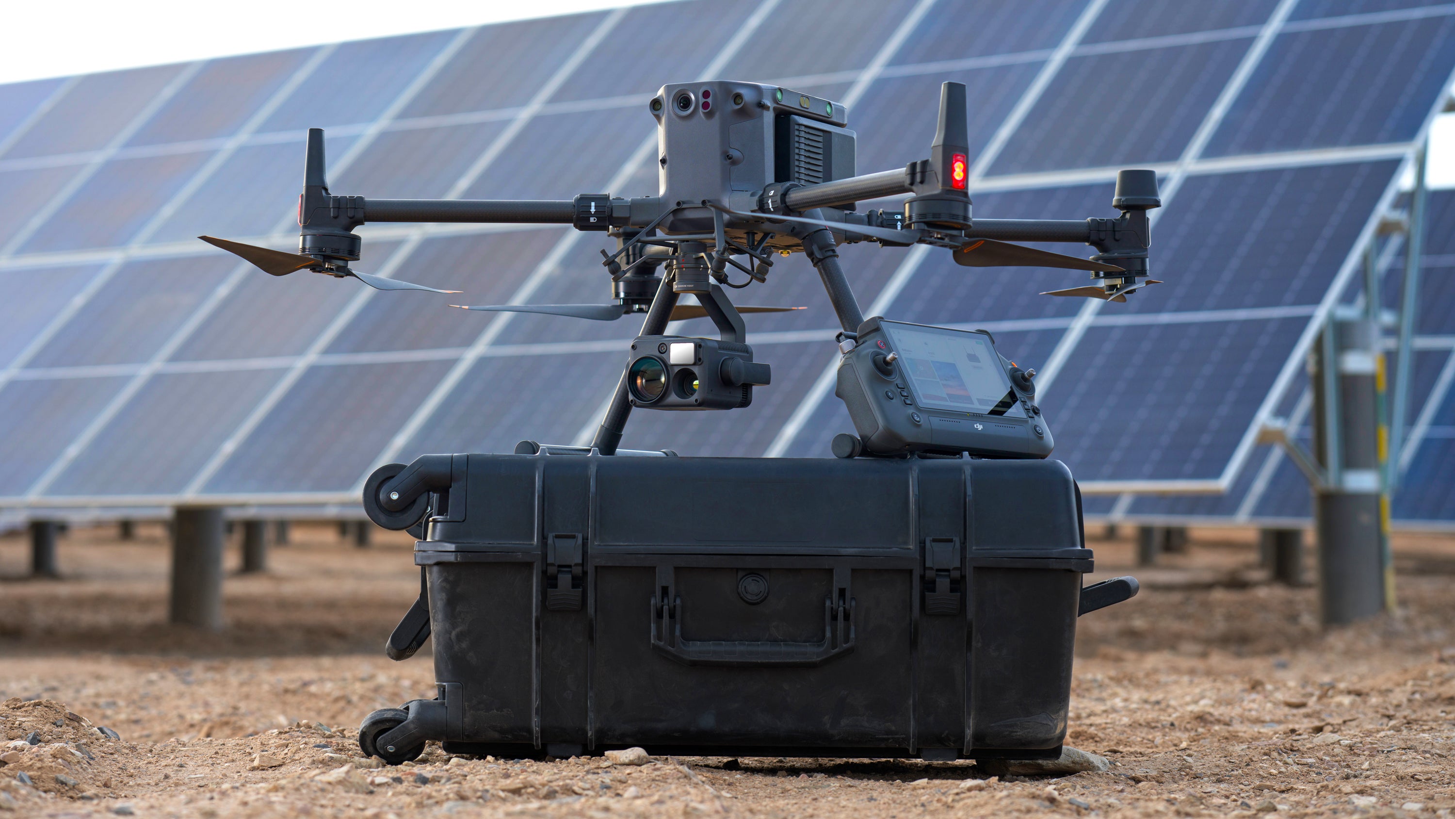 تعمل DJI Matrice 350 RTK على إيقاف تشغيلها فوق حقيبة حملها المتدحرجة ، بجانب مجموعة كبيرة من الطاقة الشمسية.