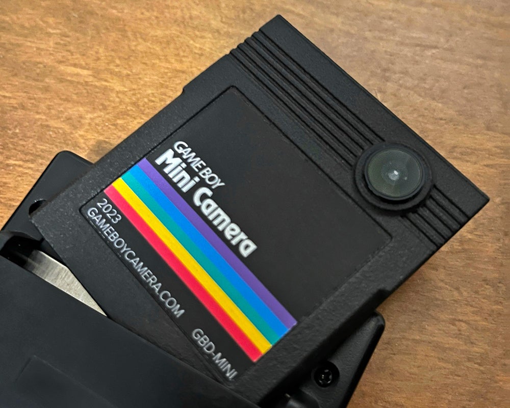 تم إدخال نصف خرطوشة كاميرا Game Boy Mini في جهاز Game Boy محمول باليد.