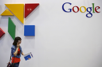 A woman walks past a logo of Google at the Global Mobile Internet Conference in Beijing.
