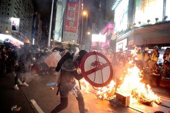 A protestor uses a shield to cover himself as he faces policemen in Hong Kong, Saturday, Aug. 31, 2019.