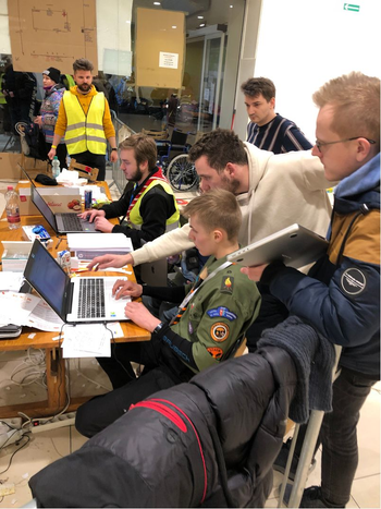 Tech workers sit in front of laptops at a refugee camp