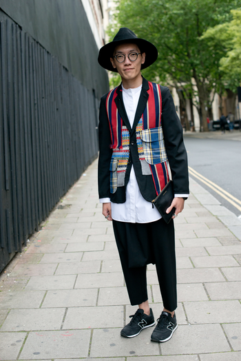 LONDON, ENGLAND - JUNE 16: Student Yongyang Hoon wears Comme Des Garcon trousers, coat and bag, New Balance trainers, Celine shirt and Reinhard Plank hat on day 2 of London Collections: Men on June 16, 2014 in London, England. (Photo by Kirstin Sinclair/Getty Images)