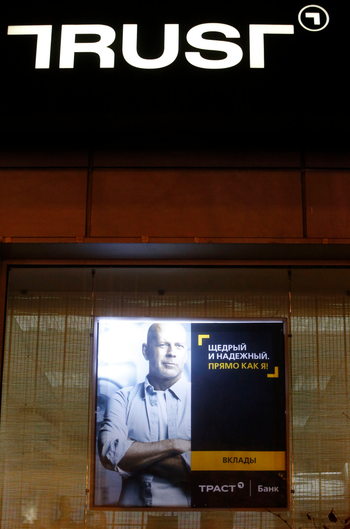 An advertisement for Trust Bank, featuring an image of Hollywood actor Bruce Willis, is on display outside a bank branch in Moscow, December 22, 2014. Russian mid-sized lender Trust Bank is to receive up to 30 billion roubles ($530 million) from the central bank to stop it going bankrupt in the first bailout of its kind during the current rouble crisis. Trust, which hired actor Bruce Willis as the face of a major advertising campaign, is Russia&#039;s 32nd largest lender by assets, according to Interfax data. It is the 15th biggest by private personal accounts, including deposits. REUTERS/Sergei Karpukhin (RUSSIA - Tags: BUSINESS) - RTR4IZ3E