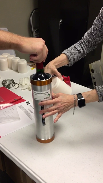 A canister is loaded with a wine bottle for a trip to the International Space Station.