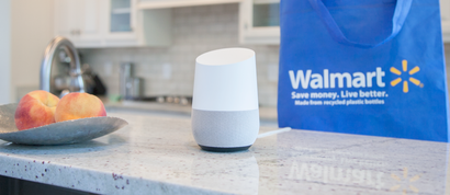 Google Home sits on a countertop in front of a Walmart bag.