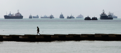 A man walks on a jetty as vessels are seen in the background, along Singapore's East Coast Park.