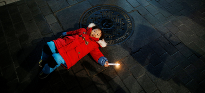 A girl holding a candle lies on a street during a protest demanding South Korean President Park Geun-hye's resignation in Seoul, South Korea, January 7, 2017.