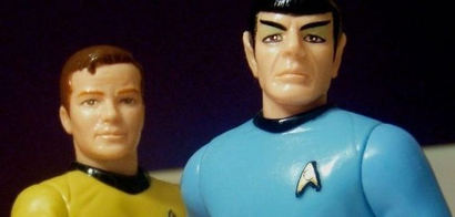 Action figures of Kirk and Spock standing next to each other, one of Kirk's arms behind Spock's back and the other pointing towards the viewer.