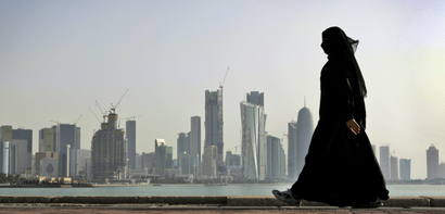 FILE - In this May 14, 2010 file photo, a Qatari woman walks in front of the city skyline in Doha, Qatar. Saudi Arabia and three Arab countries severed ties to Qatar on Monday, June 5, 2017 and moved to cut off land, sea and air routes to the energy-rich nation that is home to a major U.S. military base, accusing it of supporting regional terror groups.