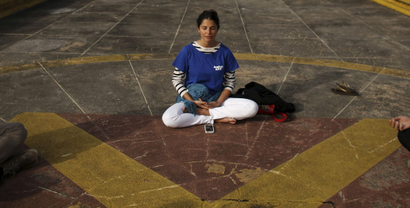 A woman meditates with her phone in front of her on the ground
