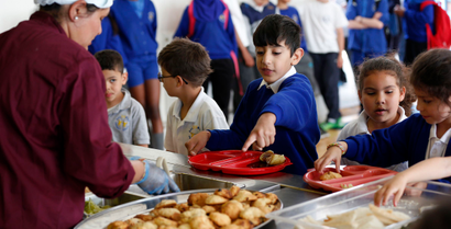 Students receive their lunch at Salusbury Primary School in northwest London June 11, 2014. This September, a new government scheme plans to give free meals to all reception, year 1 and 2 students registered in England's state-funded schools. Local media reports that this will amount to saving families about ?400 a year per child. REUTERS/Suzanne Plunkett (BRITAIN - Tags: EDUCATION SOCIETY FOOD) - RTR3T86S