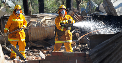 Members of the Country Fire Authority (CFA) put out smothering fires after a fast moving bushfire took out at least three homes in the Warrandyte suburb of Melbourne, Australia, 10 February 2014. A total fire ban is in place across Victoria during the heat wave temperatures while several fires are burning throughout the state.
