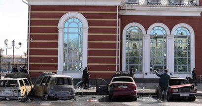 Damaged cars and debris are shown outside of a brick building in Ukraine.