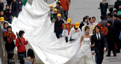 Chinese pedestrians watch a model wearing a 50-metre-long wedding gown on a street in Hefei, east China's Anhui province March 19, 2005. China saw 1.613 million couples divorce in 2004, an increase of 21.2 percent over the previous year, according the Ministry of Civil Affairs. CHINA OUT REUTERS/CHINA Newsphoto SUN/TC - RP6DRMVGCUAB