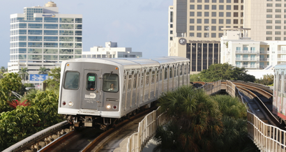 Miami's Metrorail train rumbles between buildings and over treetops.