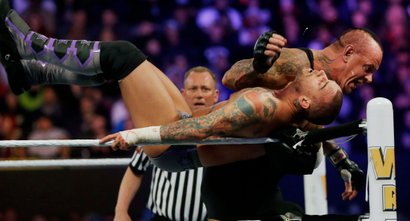 Wrestler Mark William Calaway, known as Undertaker, right, hits Phillip Jack Brooks known as CM Punk as they wrestle Sunday, April 7, 2013, in East Rutherford, N.J., during Wrestlemania. (AP Photo/Mel Evans)