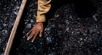A hand touching a pile of coal