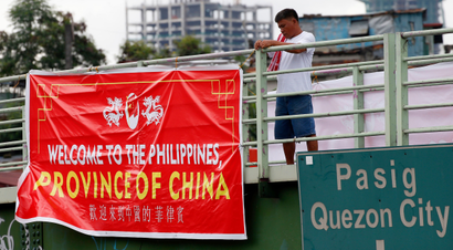 A man tries to remove a tarpaulin banner with the words "Welcome to the Philippines, Province of China" that was hung from an overpass Thursday, July 12, 2018, in Manila, Philippines. Similar banners have been seen in Manila Thursday which coincided with the second anniversary of the United Nations Permanent Court of Arbitration's decision upholding the Philippines' territorial rights on some islands, shoals, and reefs in the disputed Spratlys Group of islands in the South China Sea. The decision was shelved by President Rodrigo Duterte and was never recognized by China.