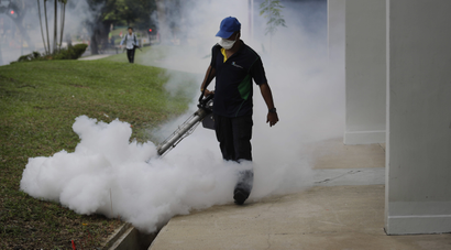 A pest control worker fumigates in Singapore to fight Zika