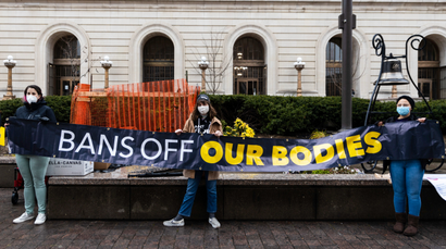 A protest banner against abortion restriction reads "bans off our bodies"