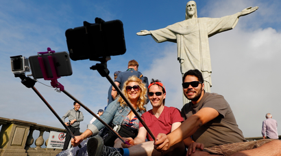 Tourists pose for selfies in front of Christ the Redeemer.