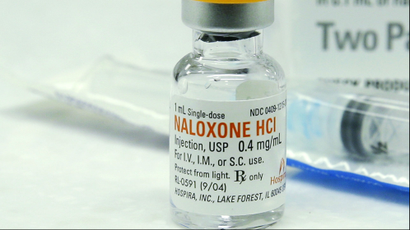 A vial of naloxone next to a syringe.