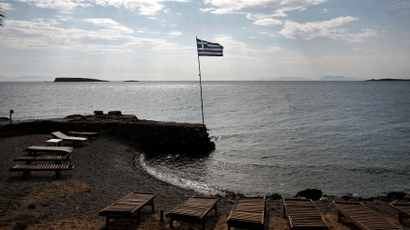 A Greek flag flutters at a beach southeast of Athens