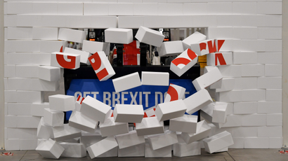 Britain's Prime Minister and Conservative leader Boris Johnson drives a Union flag-themed JCB, with the words "Get Brexit Done" inside the digger bucket, through a fake wall emblazoned with the word "GRIDLOCK", during a general election campaign event at JCB construction company in Uttoxeter, Britain, December 10, 2019.