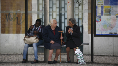 Women speak as they wait for a tram in Lisbon.