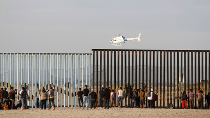 Migrants, part of a caravan of thousands trying to reach the U.S., look through the border fence between Mexico and the United States after arriving in Tijuana, Mexico,