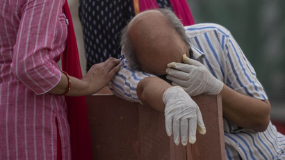 A man reacts before the cremation of his relative, who died from the coronavirus disease (COVID-19), on the banks of the river Ganges at Garhmukteshwar