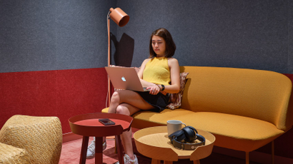 A woman with a laptop sits on a sofa in a rendering of a Spotify office of the future.