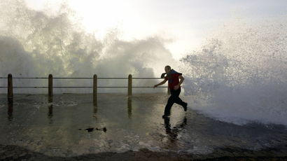 A man runs as heavy waves crash along the Sea Point beachfront in Cape Town, May 5, 2008. Waves of up to six metres are expected, driven by seasonal winter swells. REUTERS/Mike Hutchings