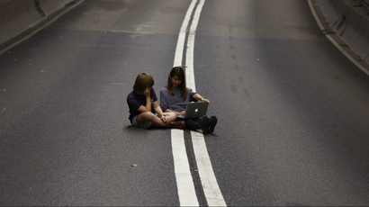 Two girls use a laptop computer on a vehicle passageway after pro-democracy protesters have blocked the traffic from going through at the financial Central district in Hong Kong early October 11, 2014.