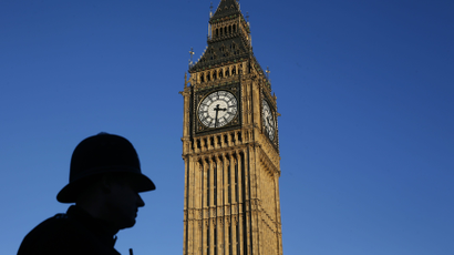 A police officer is silhouetted against the sky next to the Big Ben clock tower during sunset in central London.